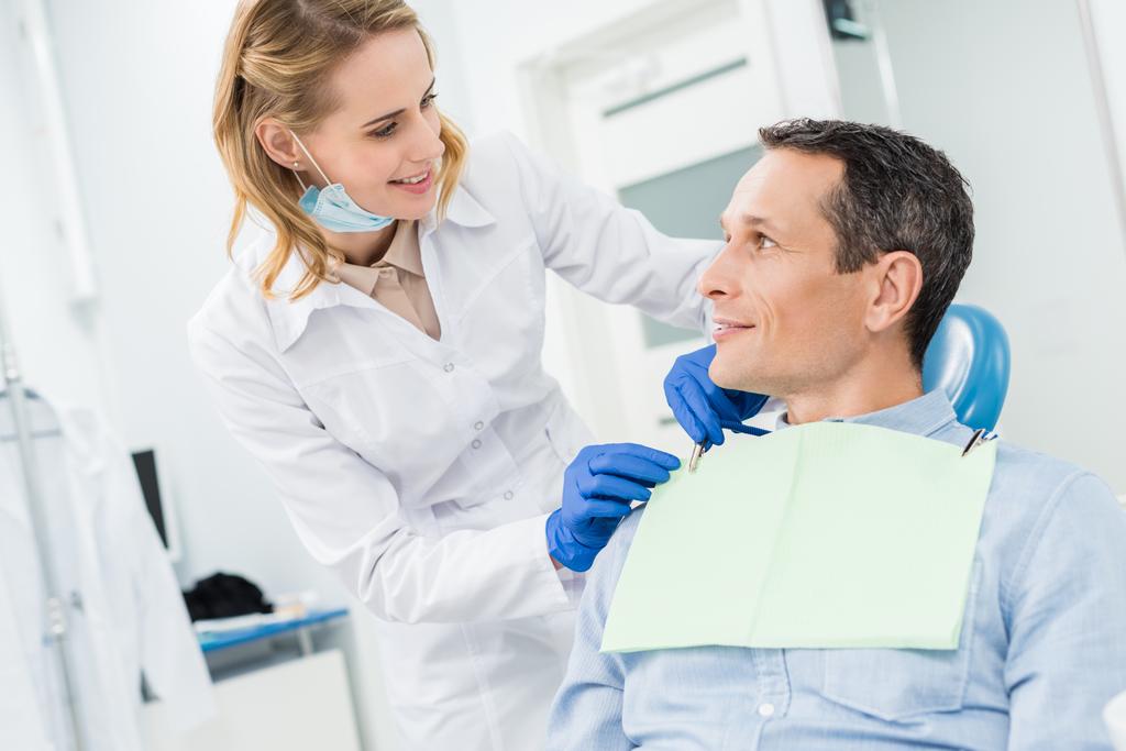 Doktor erkek hasta peçete modern diş kliniğinde sabitleme - Fotoğraf, Görsel