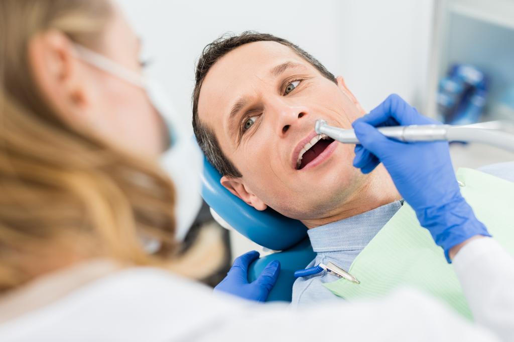 Modern diş kliniğinde dişçi matkabı kullanan erkek hasta - Fotoğraf, Görsel
