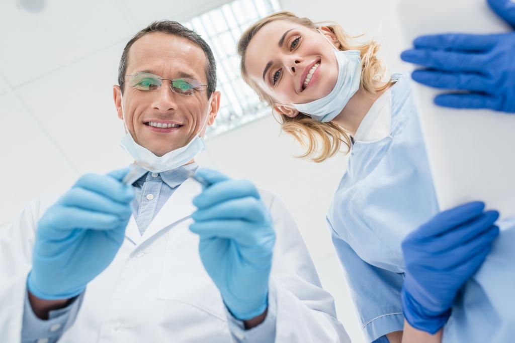 Стоматологи проверяют зубы пациентов в современной клинике
 - Фото, изображение