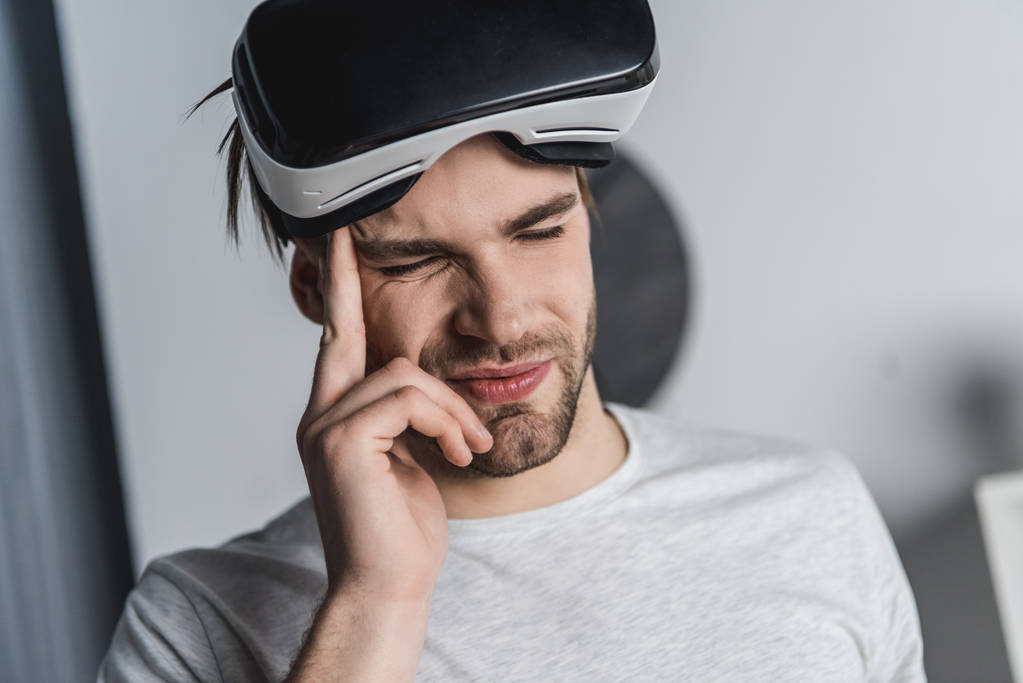 joven en auriculares de realidad virtual con dolor de cabeza
 - Foto, imagen