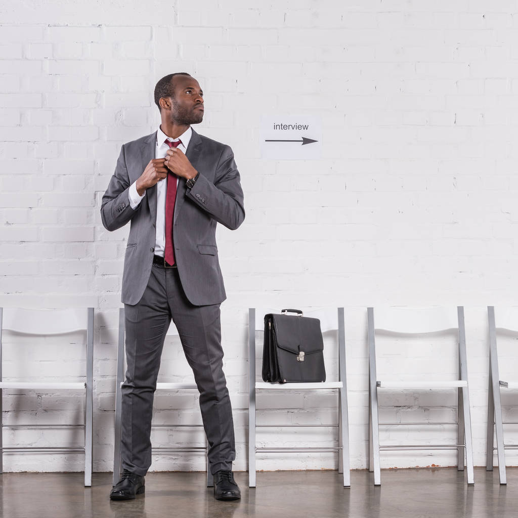 就職の面接を待っている蝶ネクタイを結ぶアフリカ系アメリカ人のビジネスマン - 写真・画像