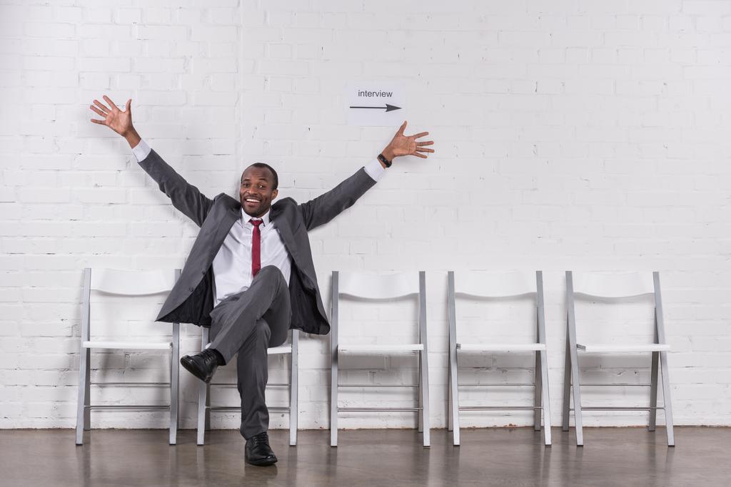sonriente hombre de negocios afroamericano con los brazos extendidos esperando entrevista de trabajo
 - Foto, Imagen