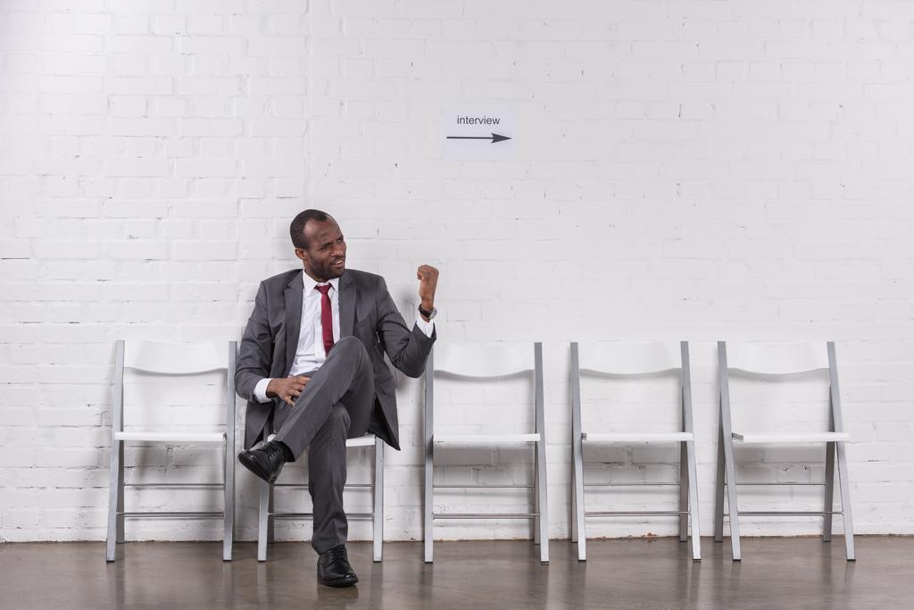 Afrikanischer amerikanischer Geschäftsmann zeigt jemandem die Faust, während er auf ein Vorstellungsgespräch wartet - Foto, Bild
