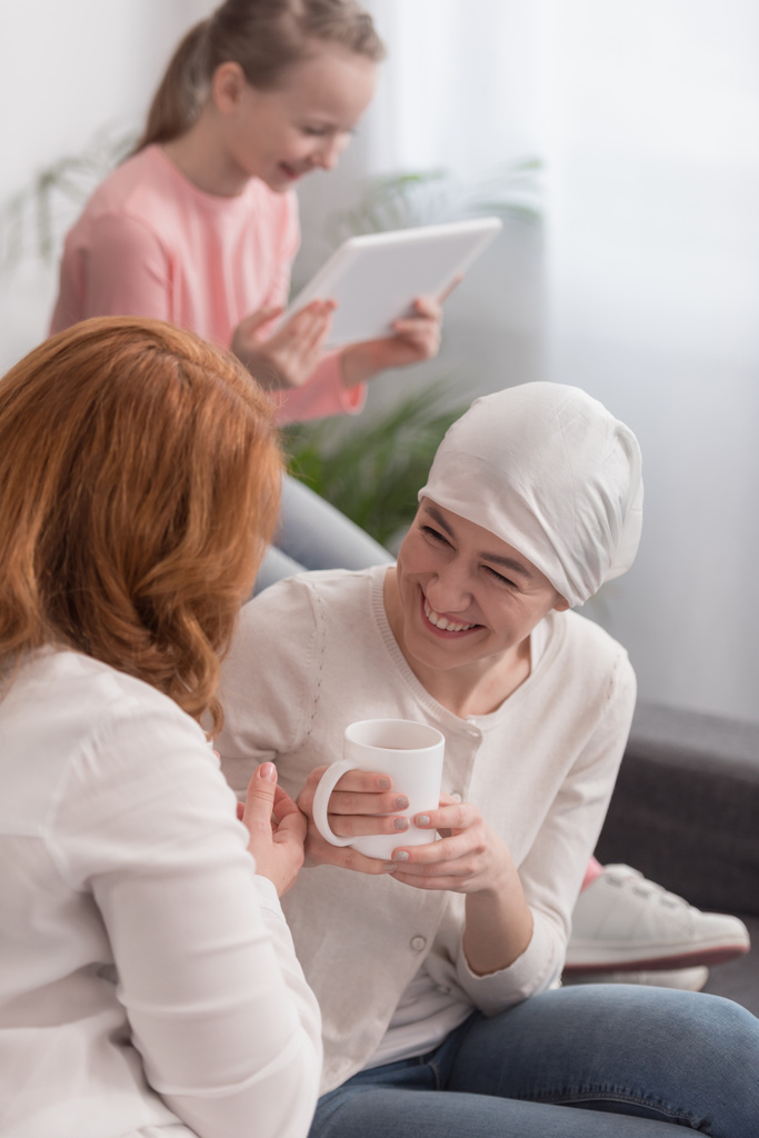femmes souriantes boire du thé et de l'enfant en utilisant une tablette numérique, concept de cancer
 - Photo, image