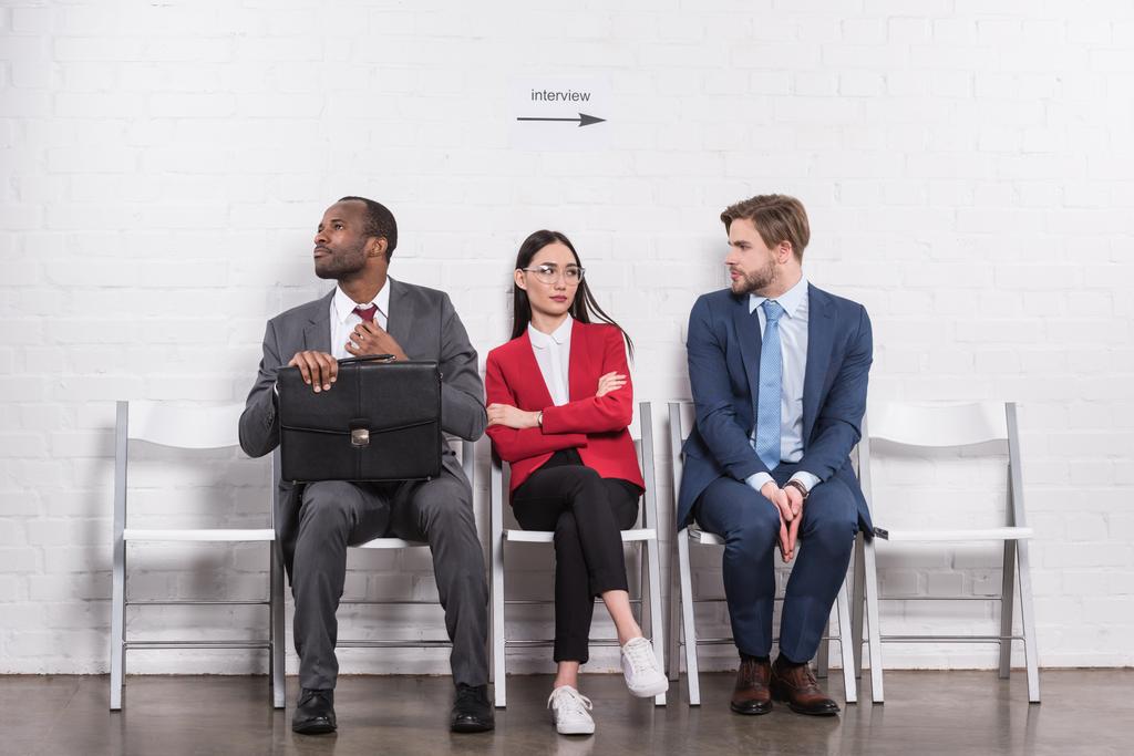 multi-etnisch business mensen zitten op stoelen tijdens het wachten voor sollicitatiegesprek - Foto, afbeelding