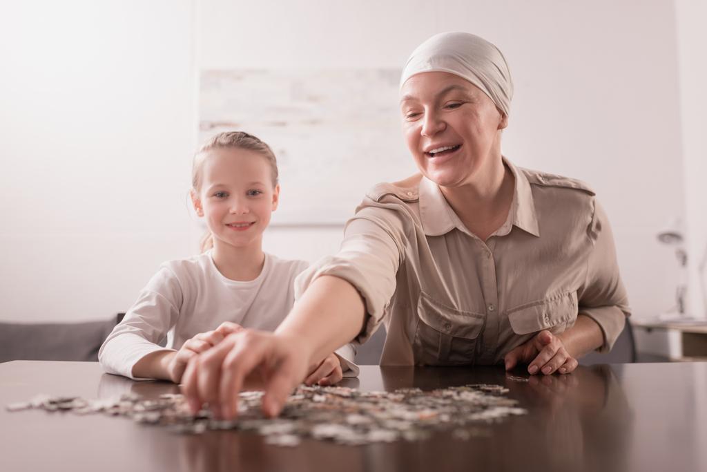 niño sonriente con abuela enferma en el pañuelo jugando con rompecabezas juntos
 - Foto, Imagen