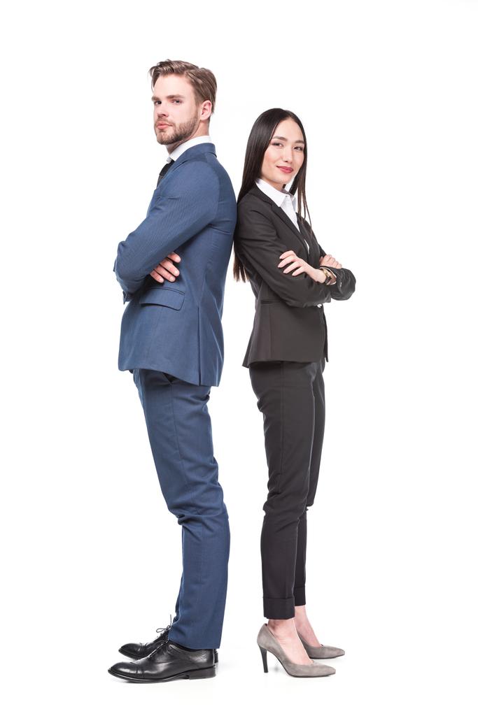 side view of multicultural business colleagues with arms crossed standing back to back isolated on white - Photo, Image