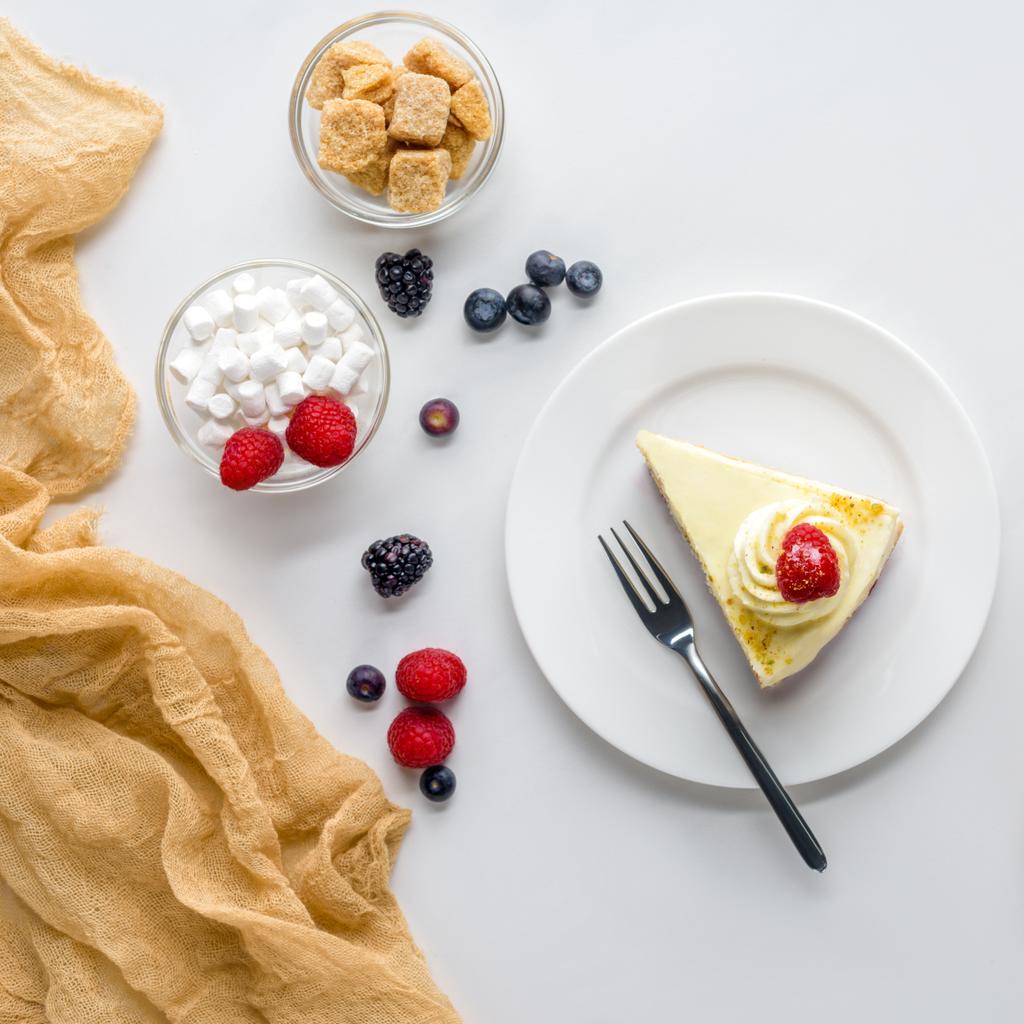 вид сверху на кусок вкусного торта с ягодами на белом столе
 - Фото, изображение