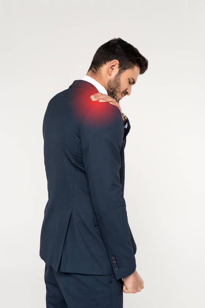 back view of young businessman suffering from ache in shoulder isolated on grey - Photo, Image