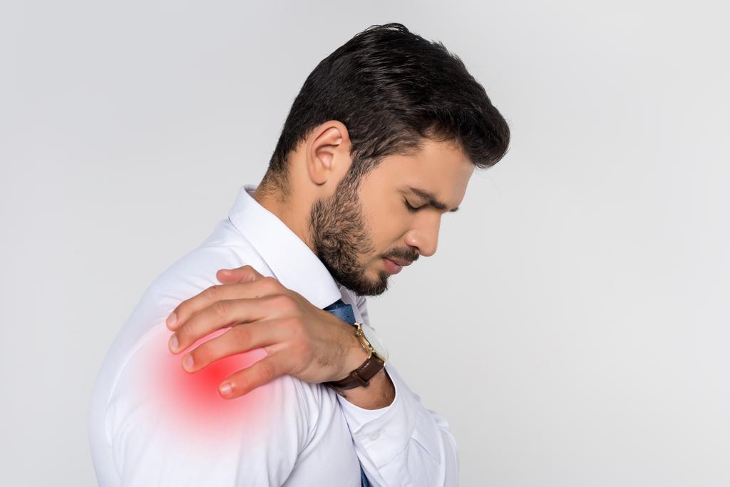 young overworked businessman suffering from pain in shoulder isolated on grey  - Photo, Image