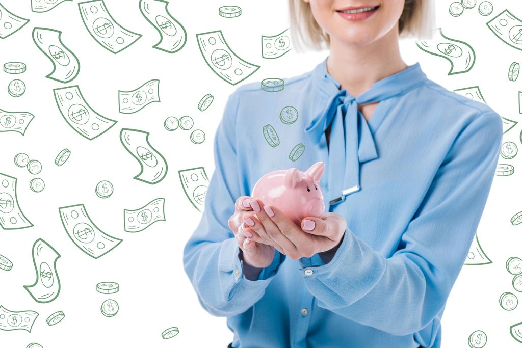 abgeschnittene Aufnahme einer Frau, die ein Sparschwein in den Händen hält, fallende Dollarnoten mit Münzsymbolen auf weißem Hintergrund - Foto, Bild
