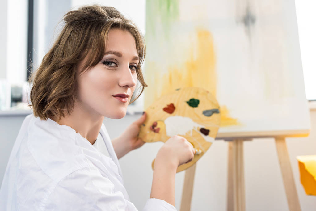 Giovane ragazza artistica miscelazione vernice in studio di luce
 - Foto, immagini