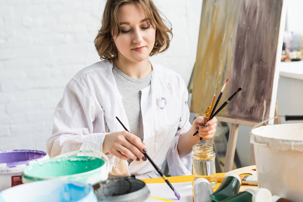Молодая творческая девушка делает образцы красок в легкой студии
 - Фото, изображение
