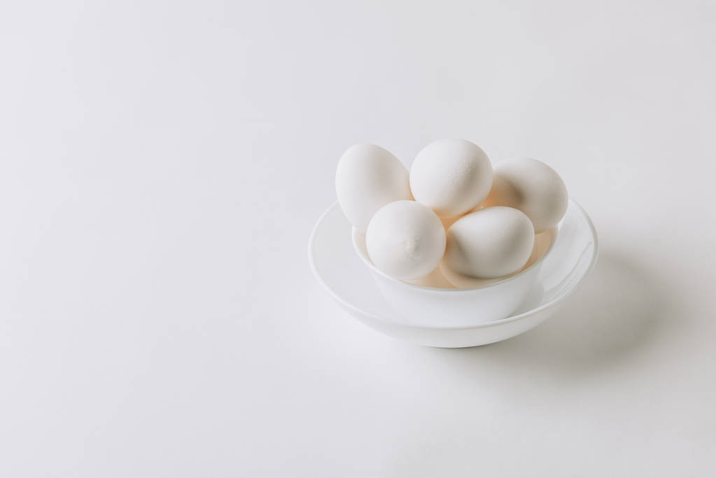 witte eieren leggen op witte plaat op witte achtergrond  - Foto, afbeelding