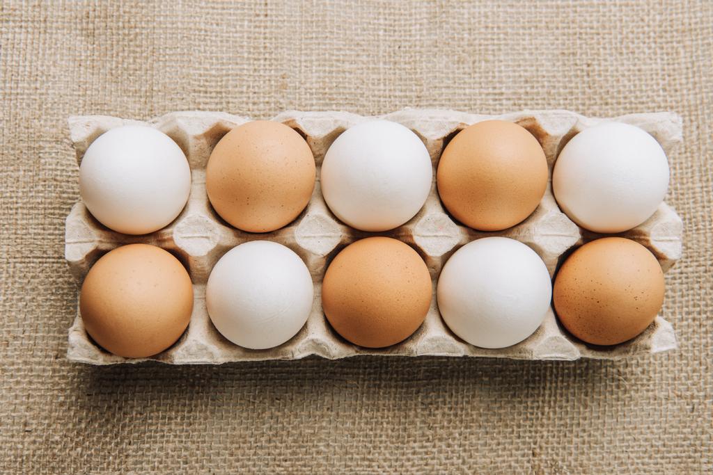 huevos blancos y marrones que ponen en el cartón del huevo en el saco
 - Foto, imagen