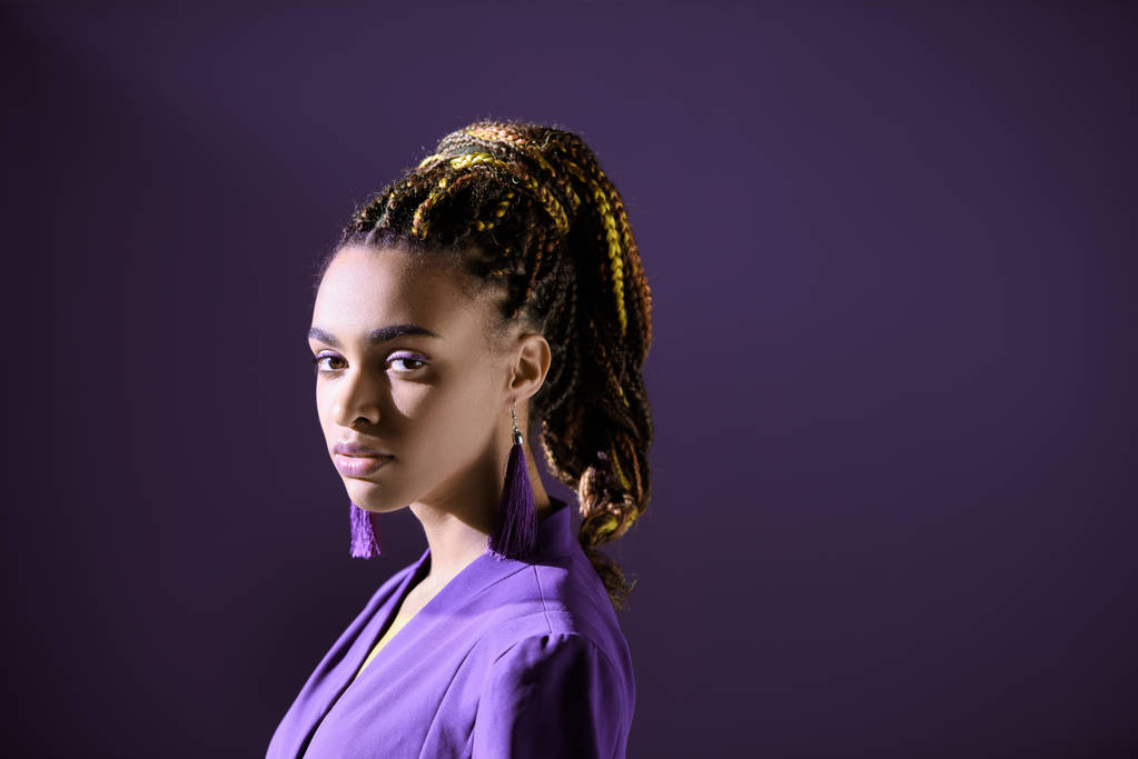 濃い紫色に分離された流行の紫ジャケットでポーズ ファッショナブルなアフリカ系アメリカ人の女の子 - 写真・画像
