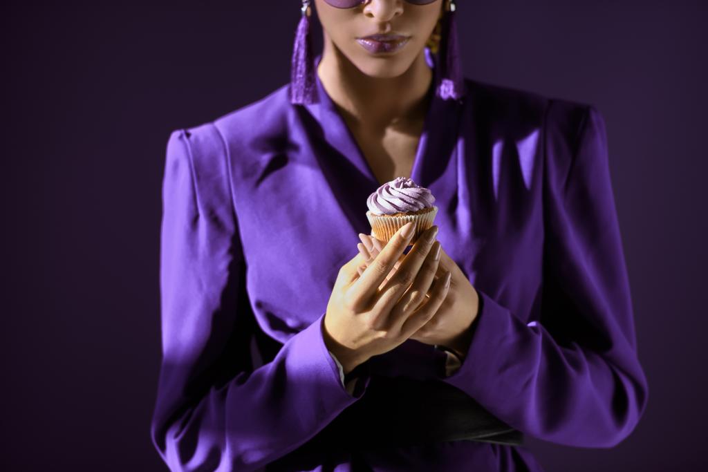 Обрізаний подання афро-американських дівчина в ультра фіолетового жакет з кекс, ізольовані на темно-фіолетовий - Фото, зображення