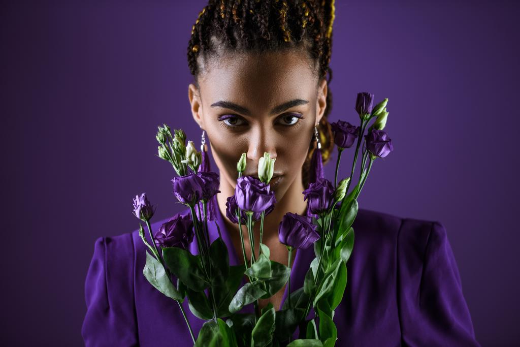 Elegáns mulatto lány pózol, lila eustoma a virágok, lila, ultra violet trend elszigetelt - Fotó, kép