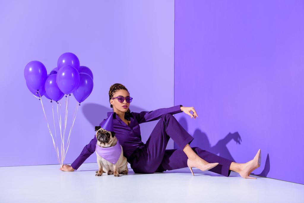 elegant african american girl posing with purple balloons and pug, ultra violet trend  - Photo, Image