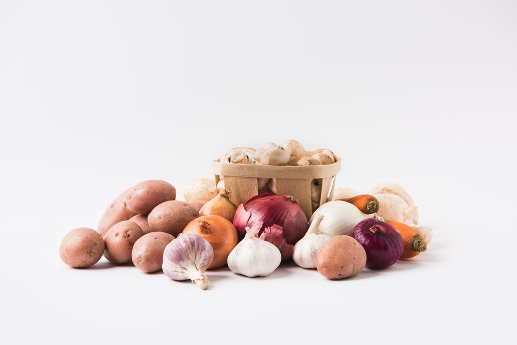 heap of mushrooms laying in basket over vegetables on white background   - Photo, Image