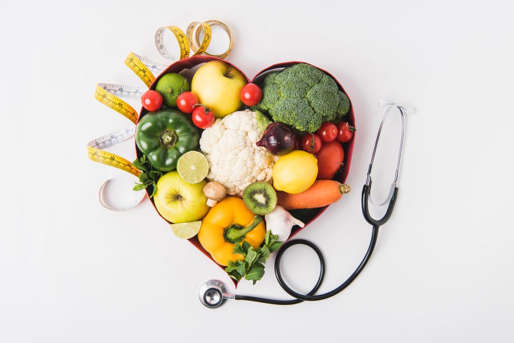 zelenina a ovoce, kterým v srdci ve tvaru misky poblíž stetoskop a vyměřuji izolované na bílém pozadí    - Fotografie, Obrázek