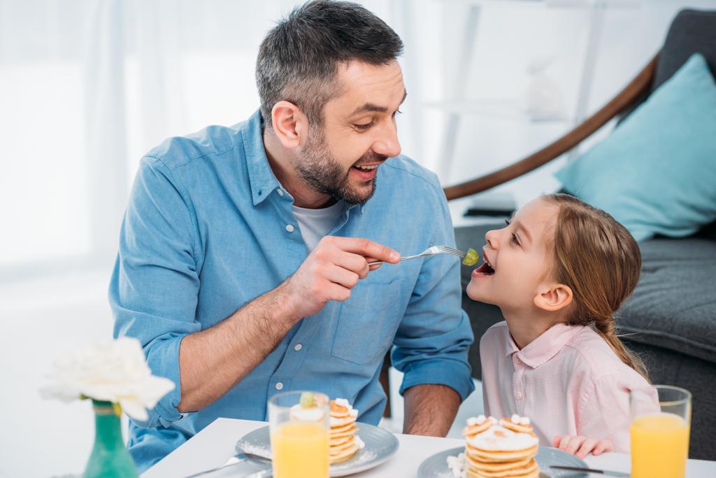 happy father and little daughter having breakfast at home - Photo, Image