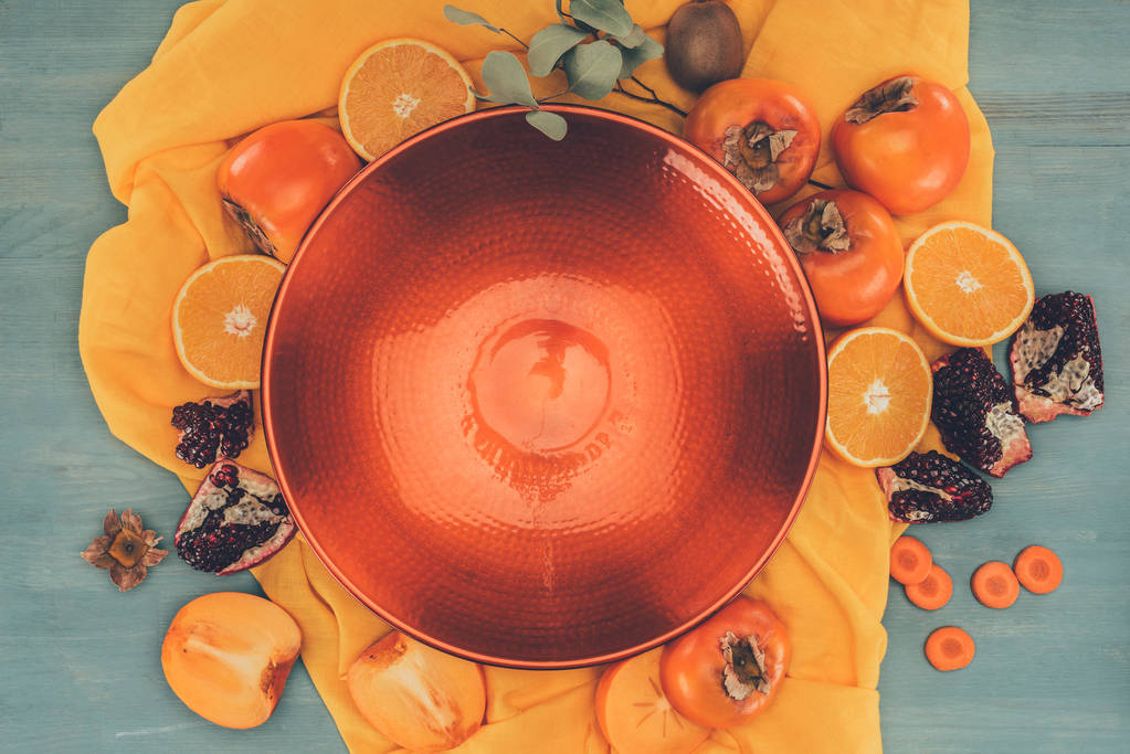 вид сверху на красную тарелку и фрукты на оранжевую скатерть
 - Фото, изображение