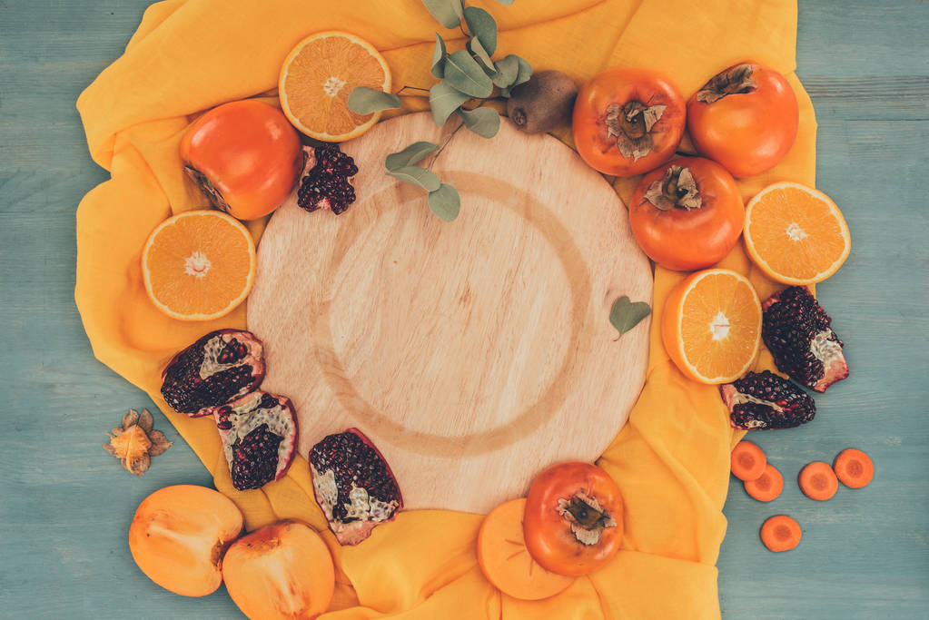 vista dall'alto del piatto in legno tra cachi con arance e melograni
 - Foto, immagini