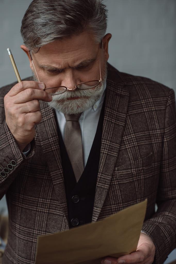 homem sênior pensativo com lápis e folha de papel
 - Foto, Imagem