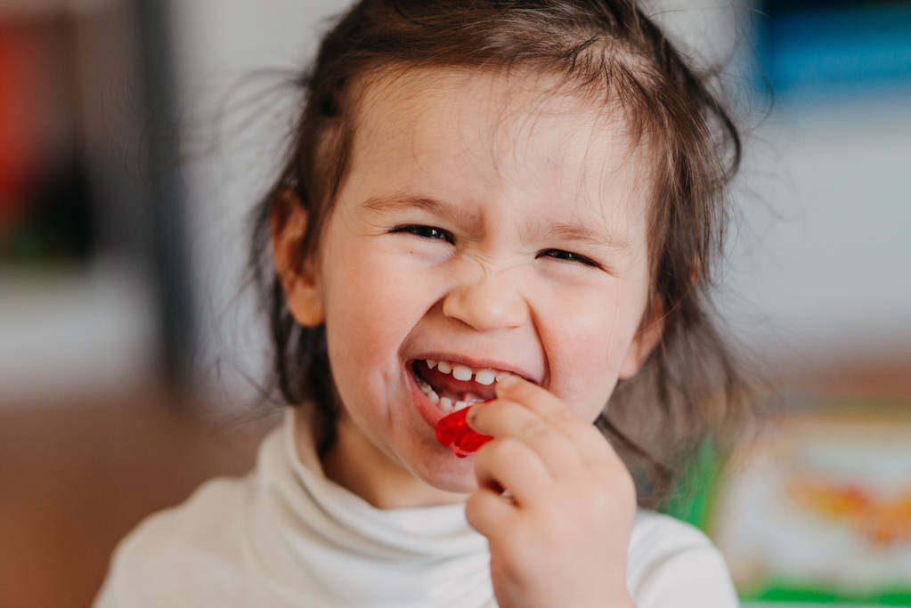 a little girl eating a jelly candys - Photo, Image