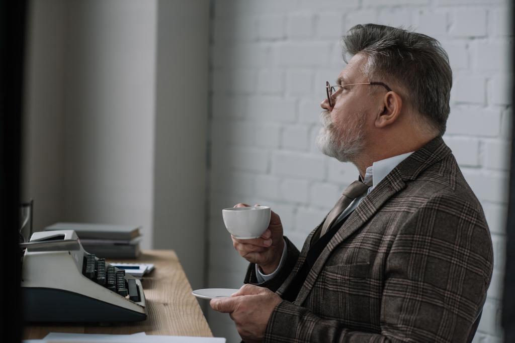 όμορφος ανώτερος συγγραφέας στο tweed κοστούμι πίνοντας καφέ στο χώρο εργασίας - Φωτογραφία, εικόνα