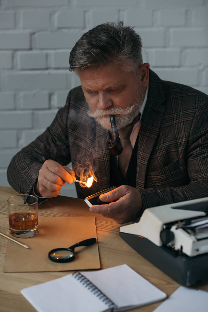 senior writer with burning match smoking pipe at workplace - Photo, Image