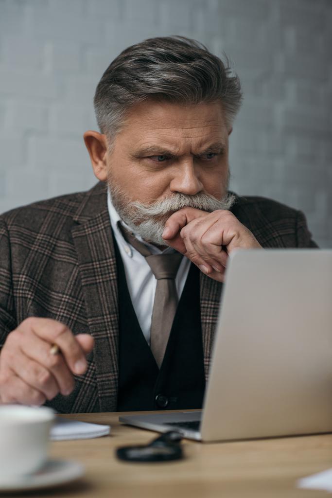 zamyšleně starší muž dívá na laptop - Fotografie, Obrázek