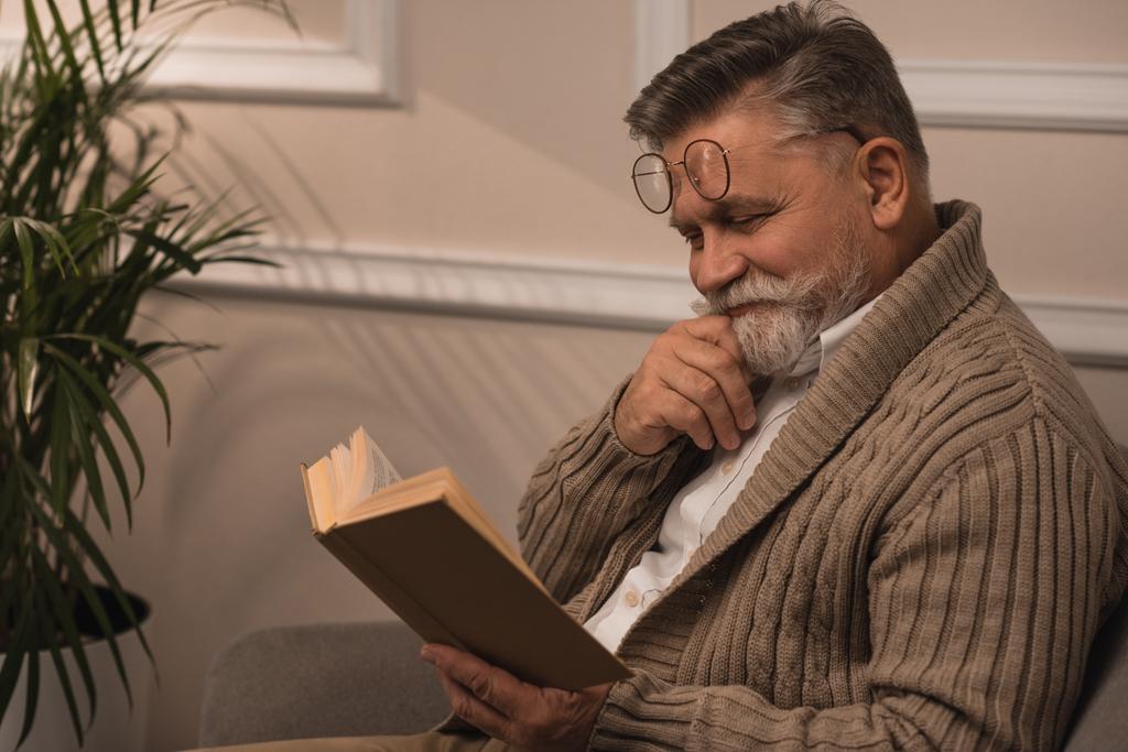 счастливый пожилой человек в свитере, читающий книгу
 - Фото, изображение