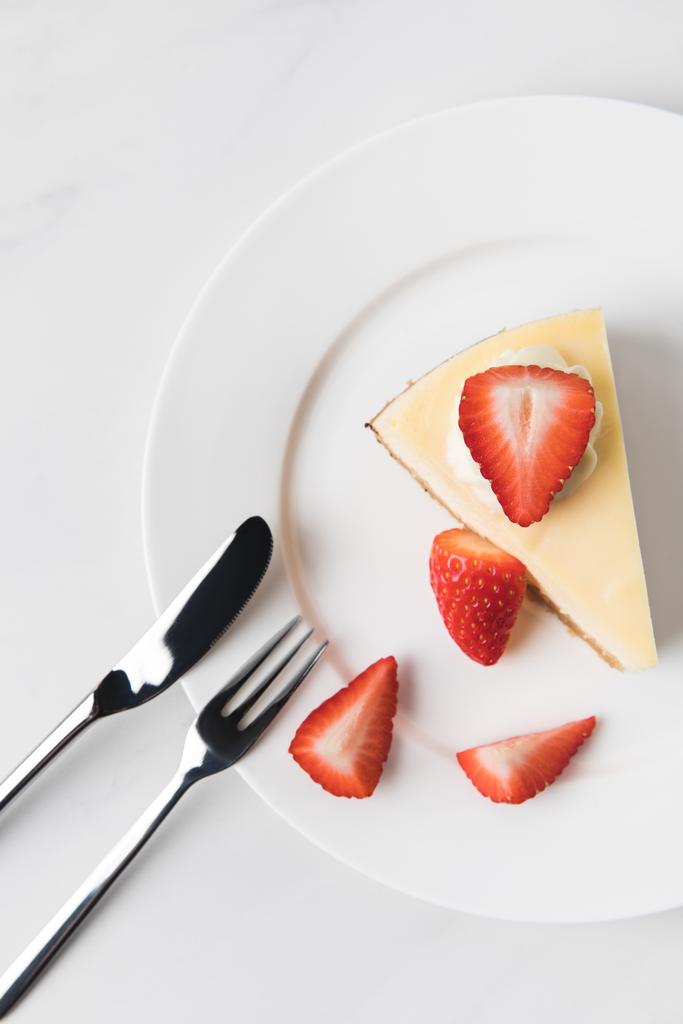Κάτοψη του cheesecake με φράουλες και τα μαχαιροπήρουνα σε λευκό - Φωτογραφία, εικόνα