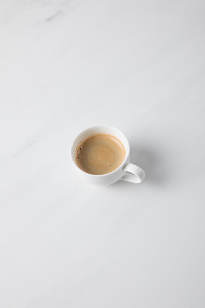 Top näkymä kahvikupin sijoitettu valkoiselle pinnalle
  - Valokuva, kuva
