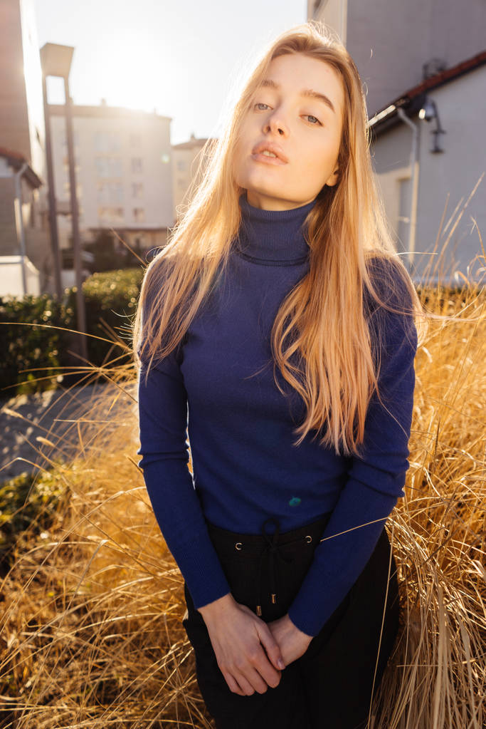 attrayant élégant fille modèle blond dans un pull bleu à la mode se promenant autour de la ville et posant
 - Photo, image