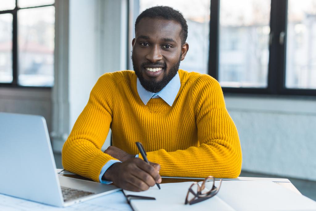 アフリカ系アメリカ人実業家持株ペンを笑顔とオフィスでカメラ目線 - 写真・画像