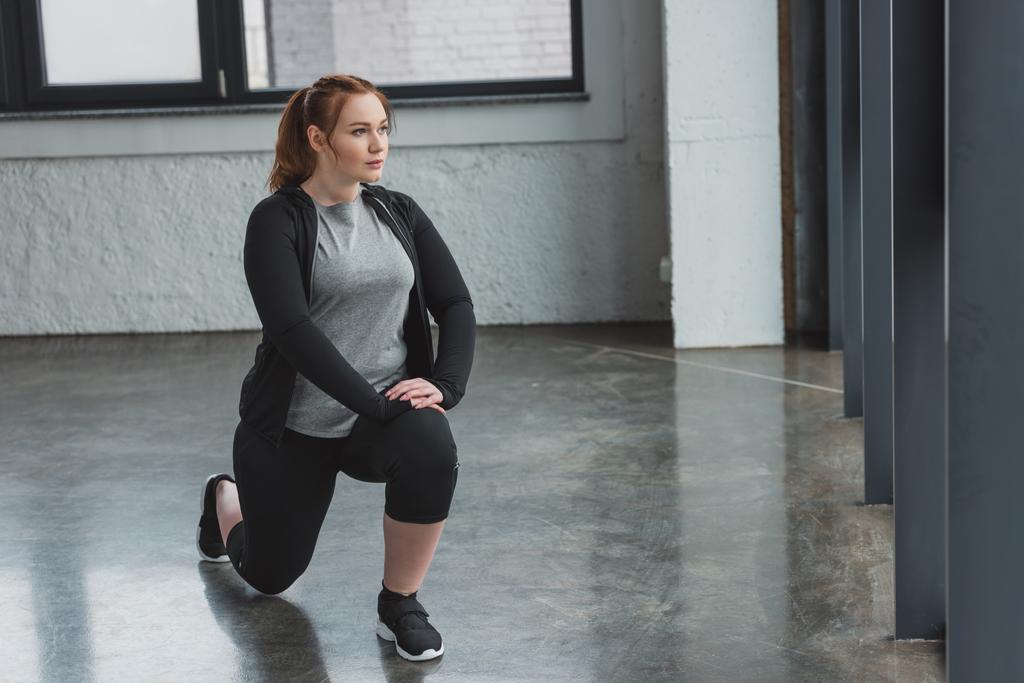 Παχύσαρκη κοπέλα που εκτελεί τεντώνοντας ασκήσεις στο γυμναστήριο - Φωτογραφία, εικόνα