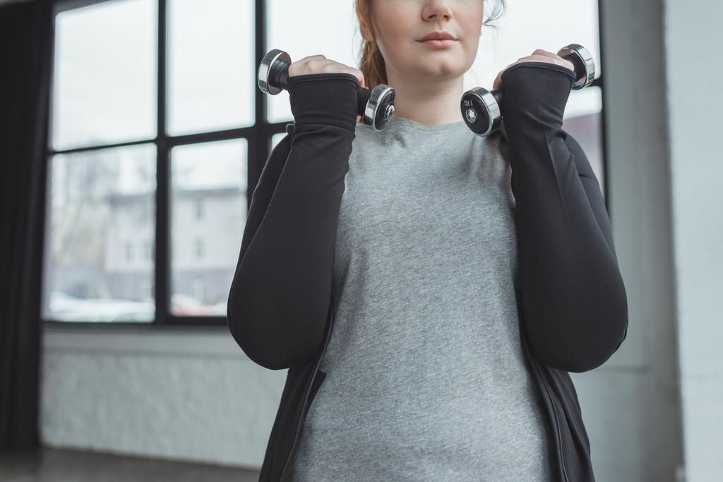 Obézní dívka trénink s činkami v posilovně - Fotografie, Obrázek