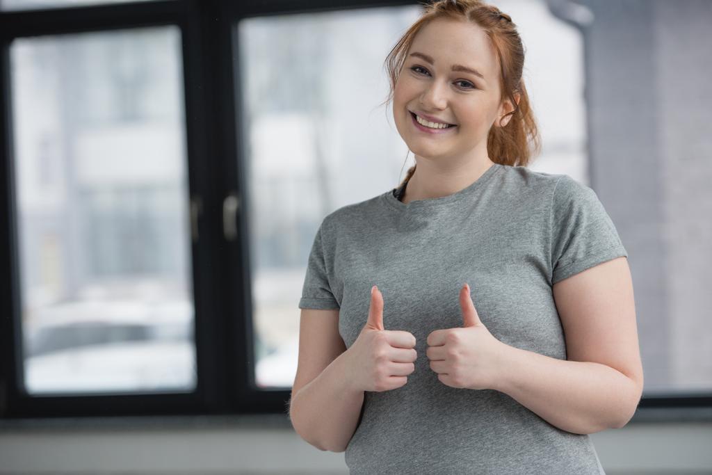 Obese girl showing thumbs up in gym - Photo, Image