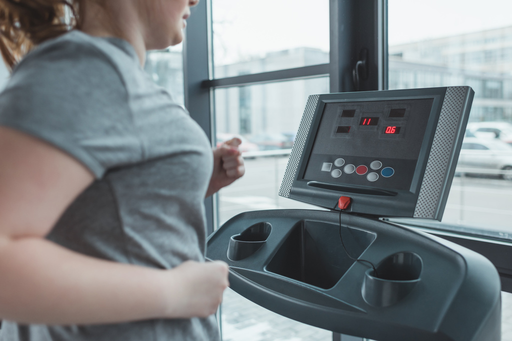 Obese girl running on treadmill in gym - Photo, Image