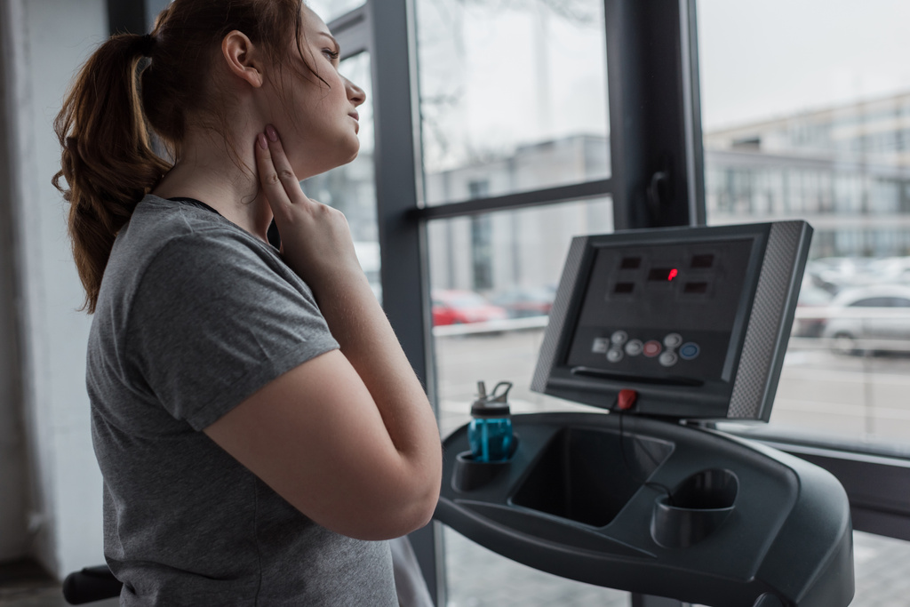 Overweight girl checking pulse during run on treadmill in gym - Photo, Image