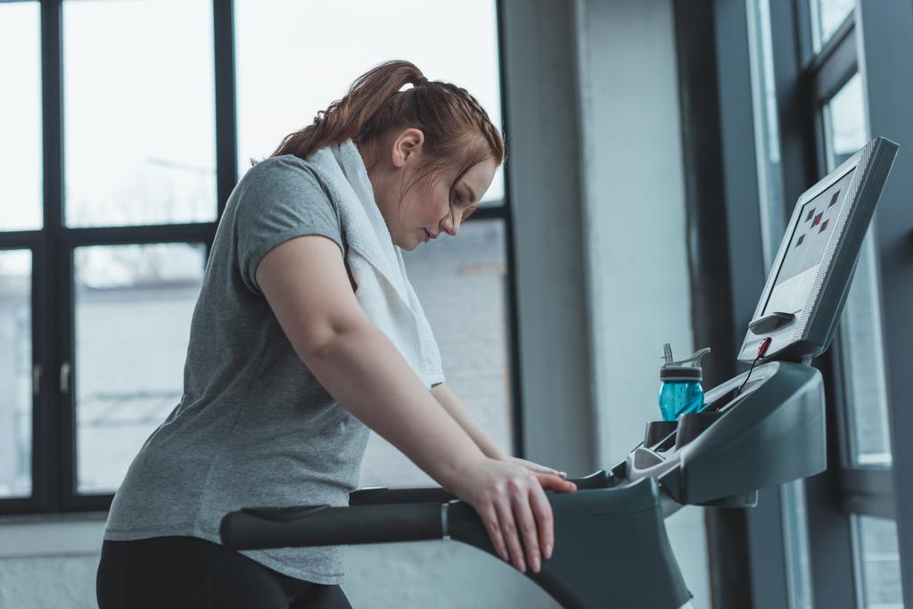 Fettleibiges Mädchen ruht sich im Fitnessstudio auf Laufband aus - Foto, Bild