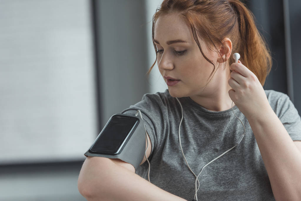 Chica con sobrepeso escuchando música en el gimnasio
 - Foto, Imagen