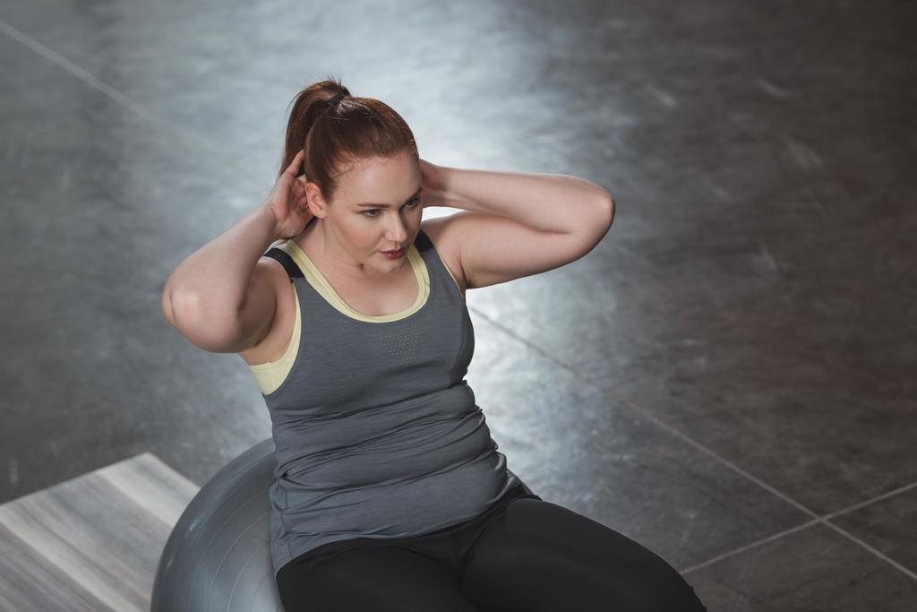 Curvy fille exerçant sur la balle de fitness dans la salle de gym
 - Photo, image