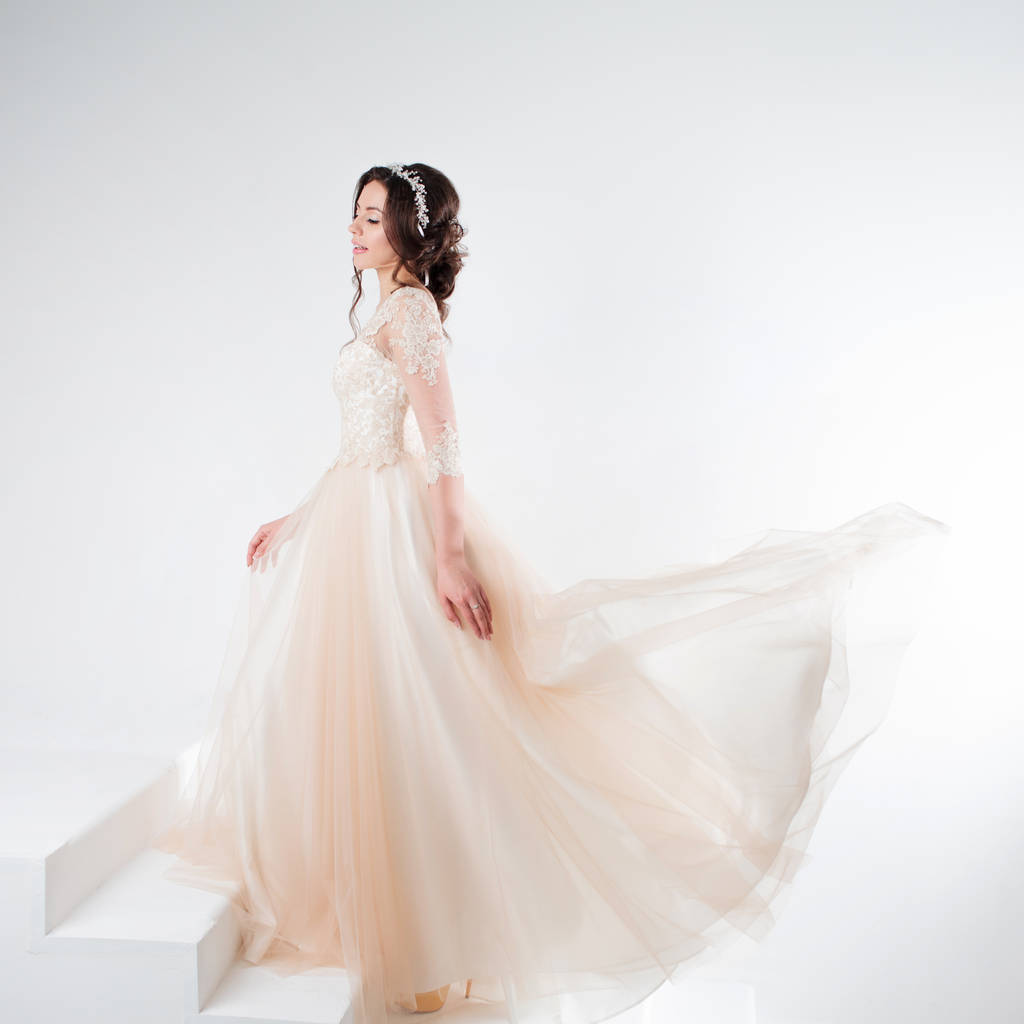 Портрет красивої дівчини у весільній сукні. Наречена в розкішній сукні, що стоїть на сходах, піднімається
 - Фото, зображення