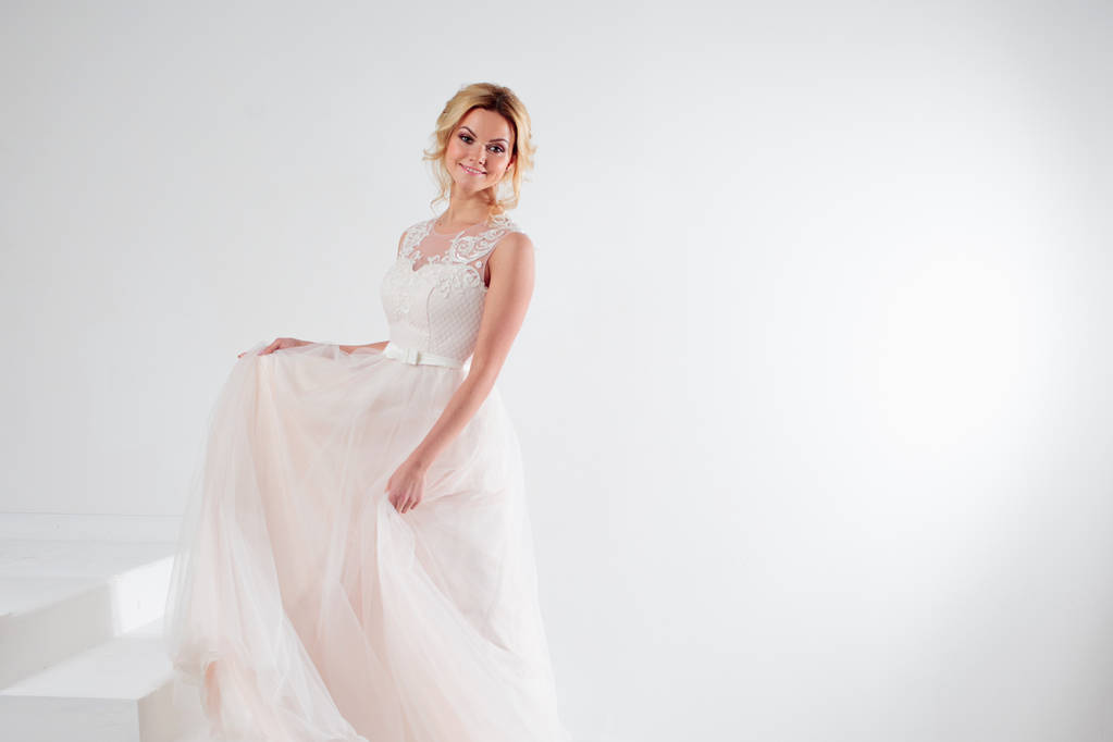 Πορτρέτο του ένα όμορφο κορίτσι σε ένα γαμήλιο φόρεμα. Νύφη, άσπρο φόντο, ελεύθερο χώρο στα δεξιά - Φωτογραφία, εικόνα