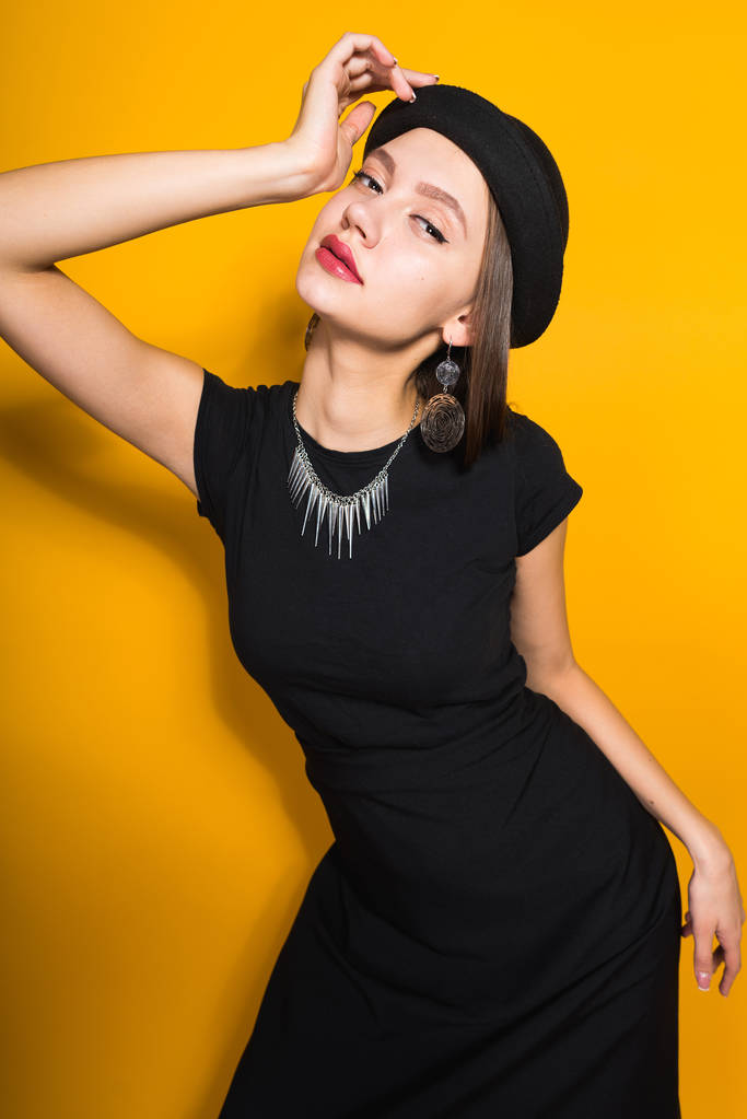 belle fille modèle attrayant en chapeau noir à la mode posant sur fond jaune, bijoux coûteux
 - Photo, image