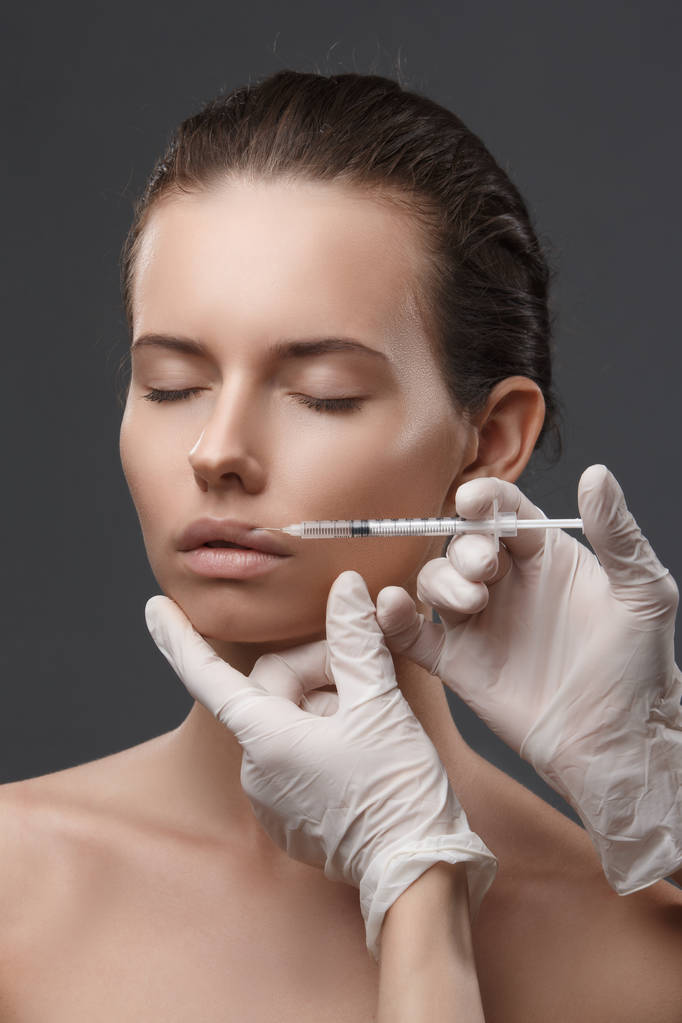 Portret van een jonge blanke vrouw die een cosmetische injectie krijgt - Foto, afbeelding